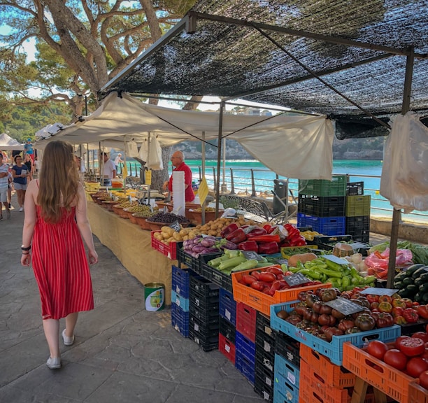 woman walking beside fruit and vegetable vendors