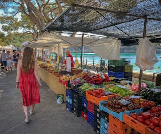 woman walking beside fruit and vegetable vendors at a market in Mallorca