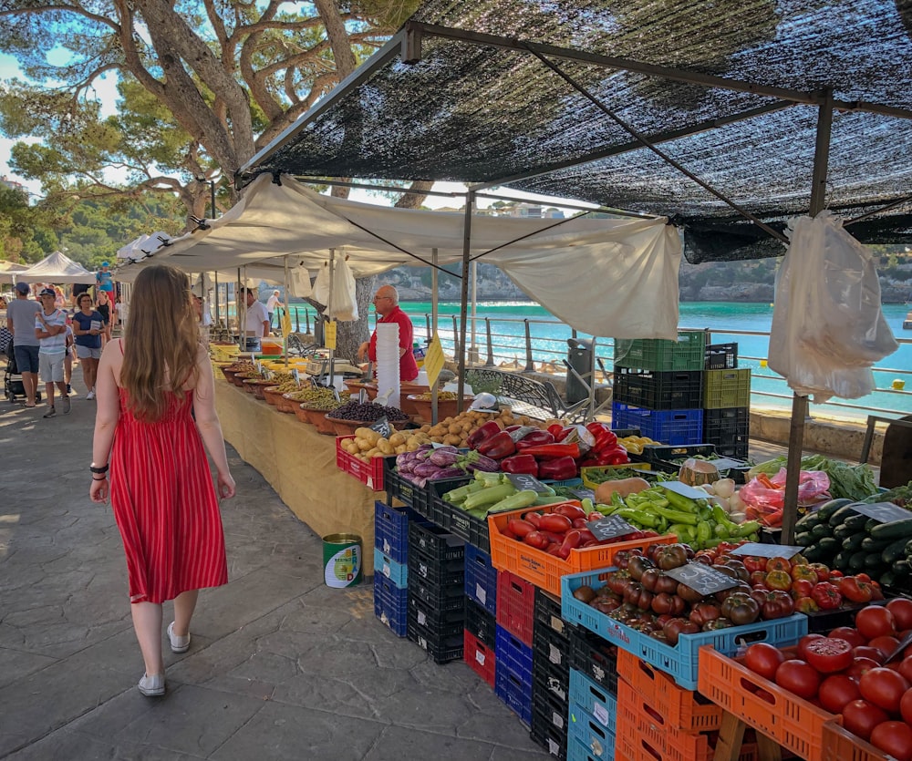 Mujer caminando junto a vendedores de frutas y verduras