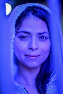 A cinematic still from a recent video project featuring a model wearing Playcast's electric blue hoodie in a moody studio.