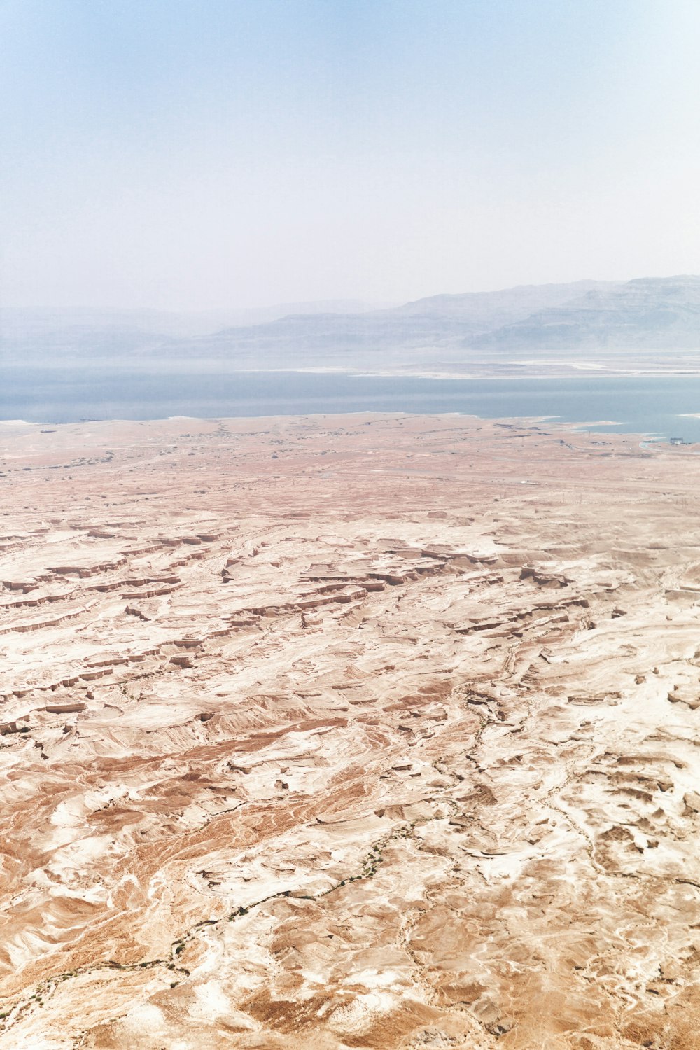 an aerial view of a desert with a body of water in the distance