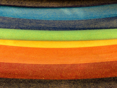 Stacks of vibrant fabric rolls in neon green, black, and white ready for production.