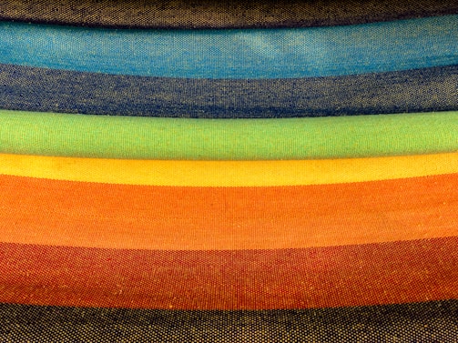 Close-up of colorful fabric rolls stacked in a bright workshop.