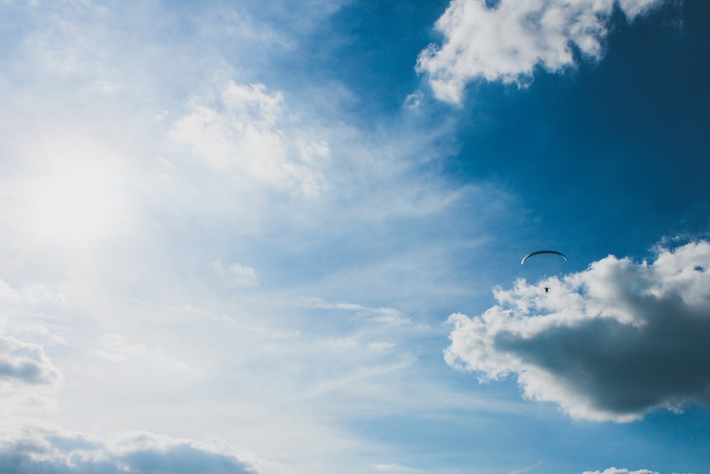 a person flying a kite in a cloudy blue sky