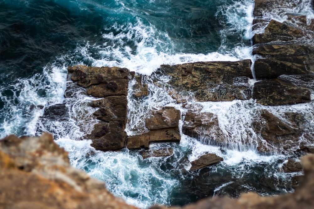 ocean water splashing on rocks during daytime