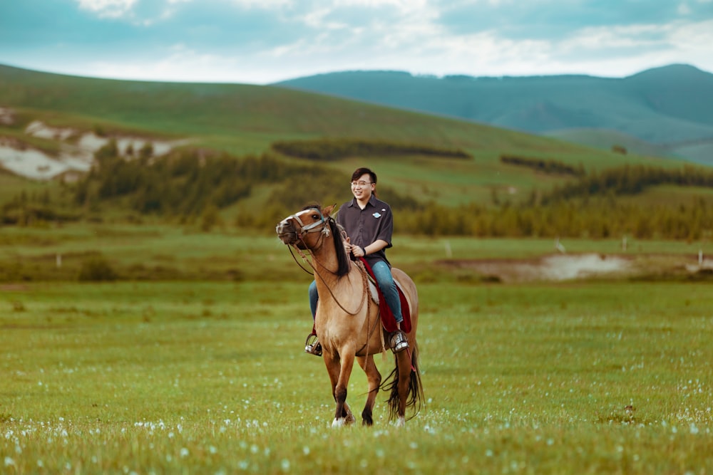person wearing gray crew-neck shirt riding brown coated horse standing on grass field