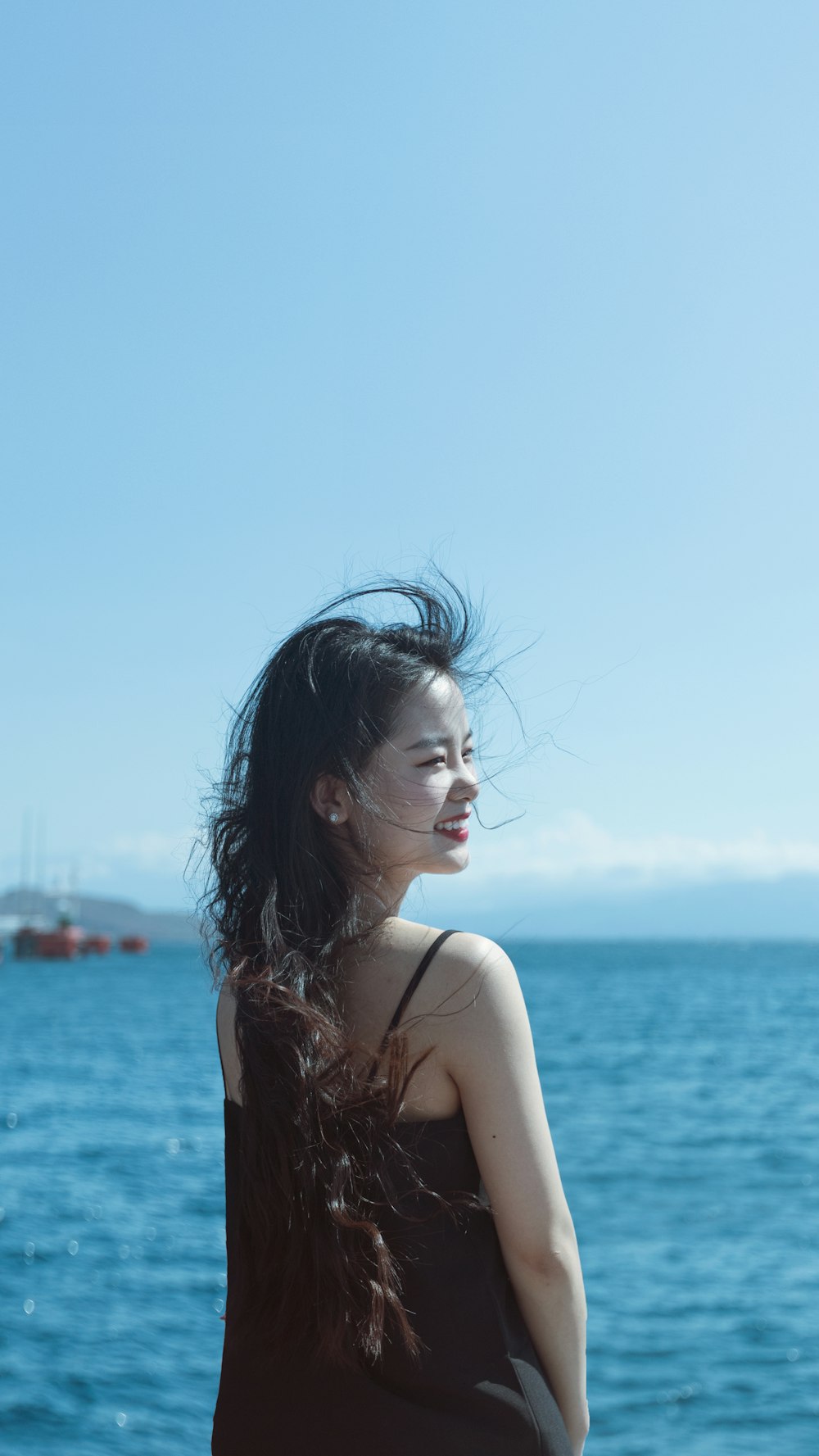 smiling woman standing near body of water during daytime