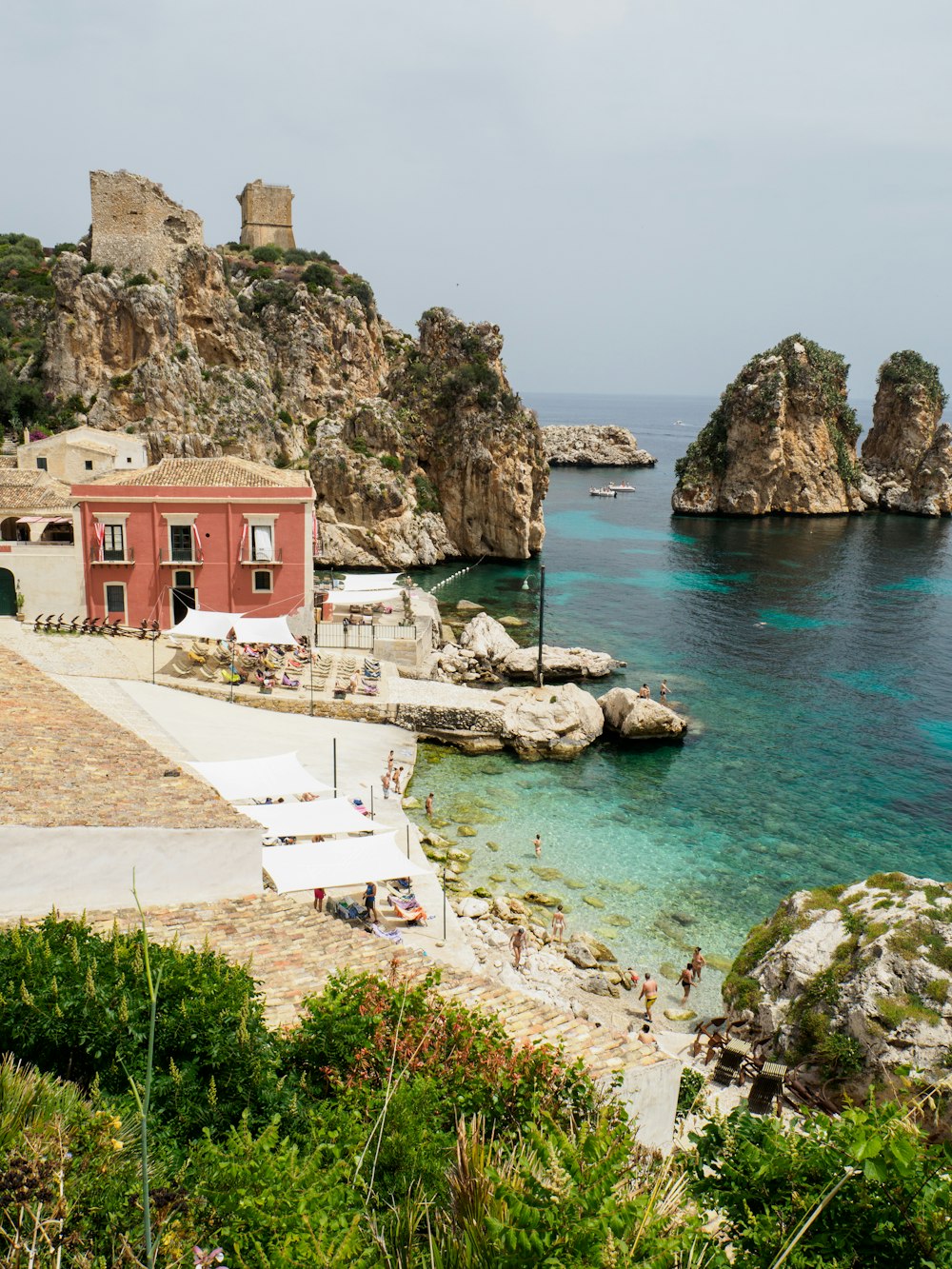 Edificio marrone vicino a una formazione rocciosa vicino a uno specchio d'acqua durante il giorno