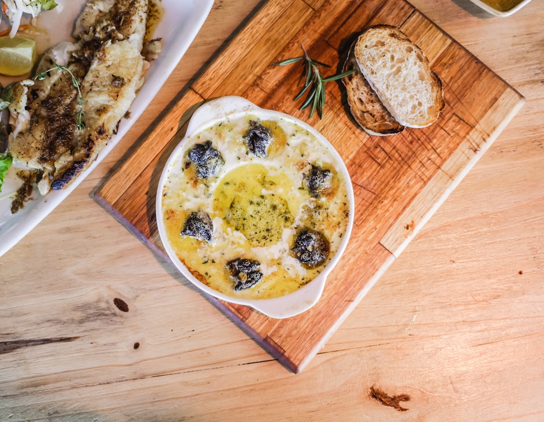 soup on white bowl on brown chopping board