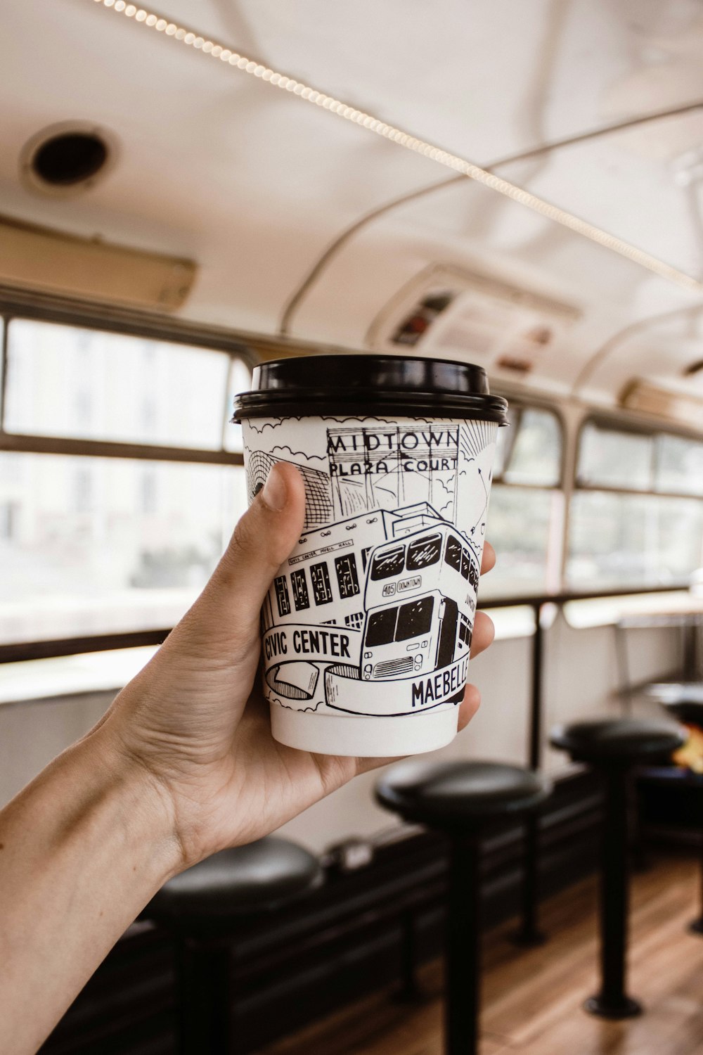 person holding white and black disposable coffee cup