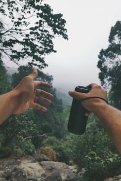 person holding sports bottle near trees