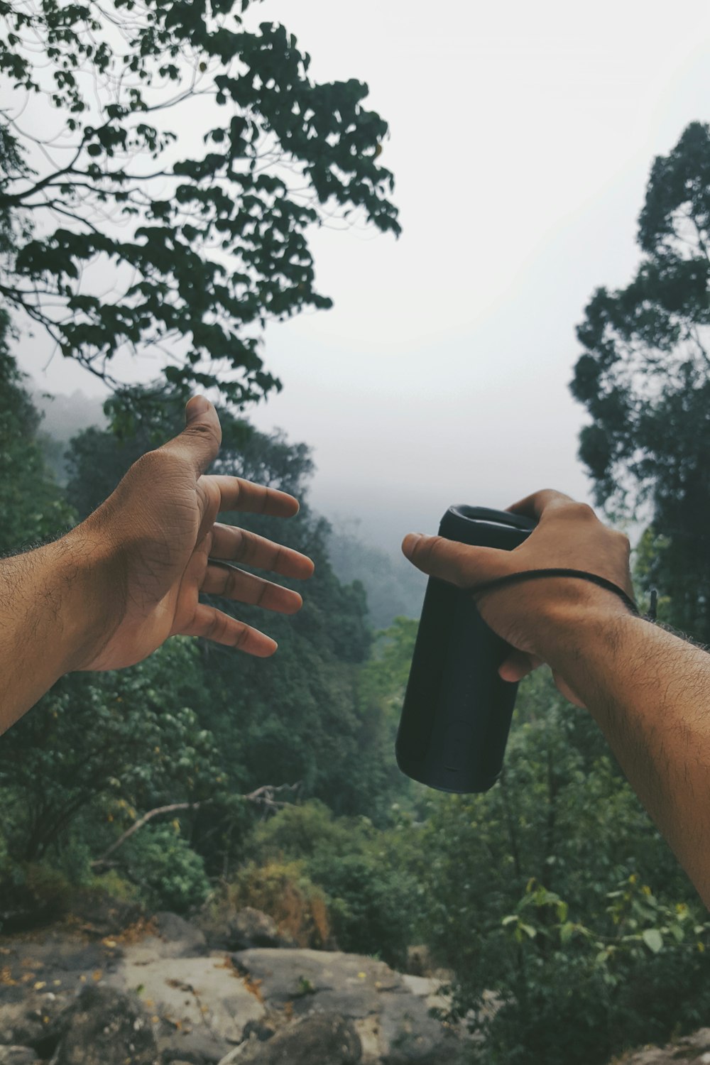 person holding sports bottle near trees