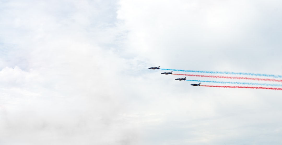 four planes releasing blue and red smokes during daytime