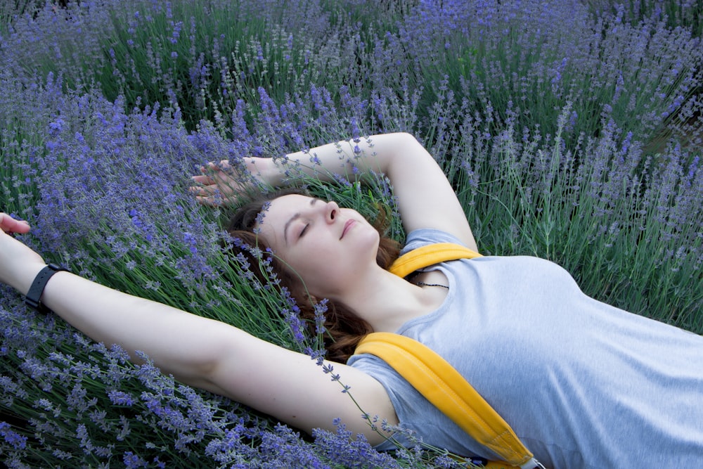 woman in gray top with yellow backpack lying on grass