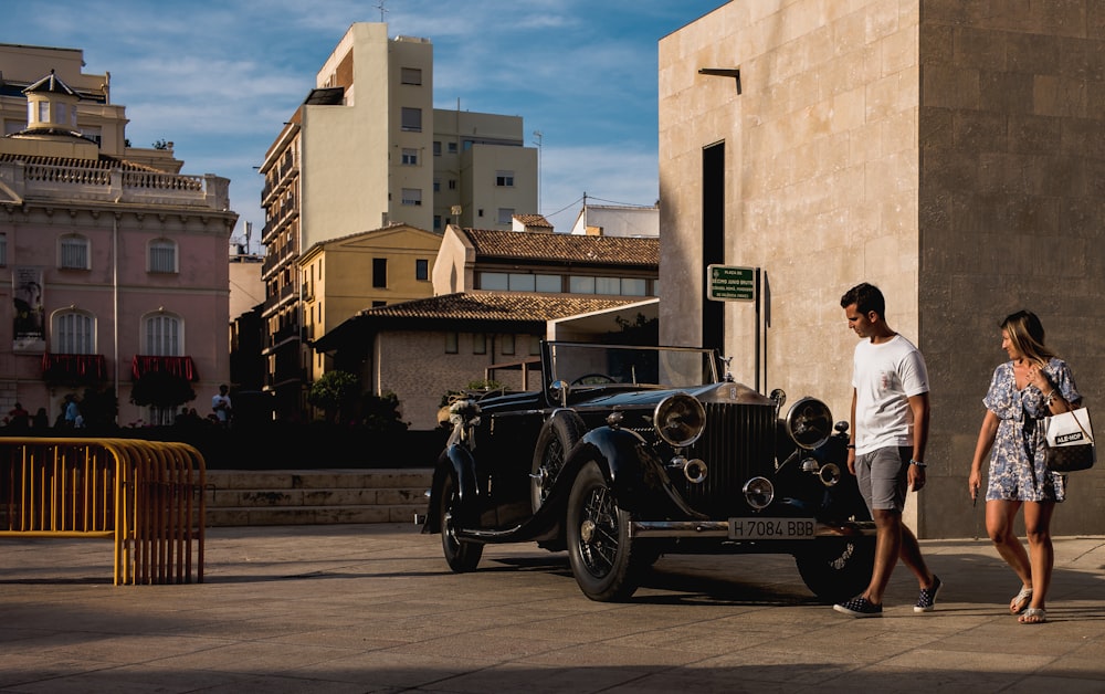 man and woman walking beside black coupe