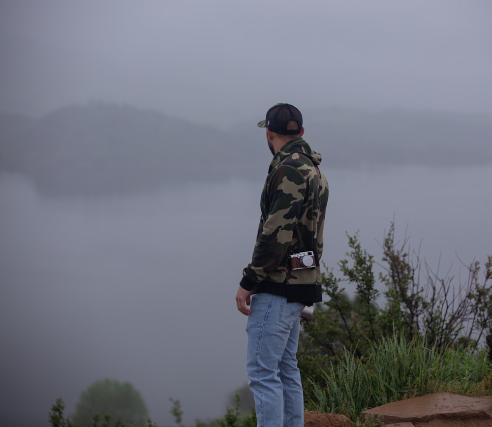 a man standing on top of a hill next to a lake