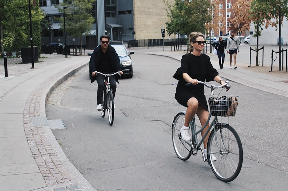 people walking and riding bikes at the street near buildings