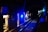 A dimly lit underground subway tunnel adorned with blue lights along the walls. The tracks extend into the darkness, and there are some electrical components and utility boxes visible along the sides.