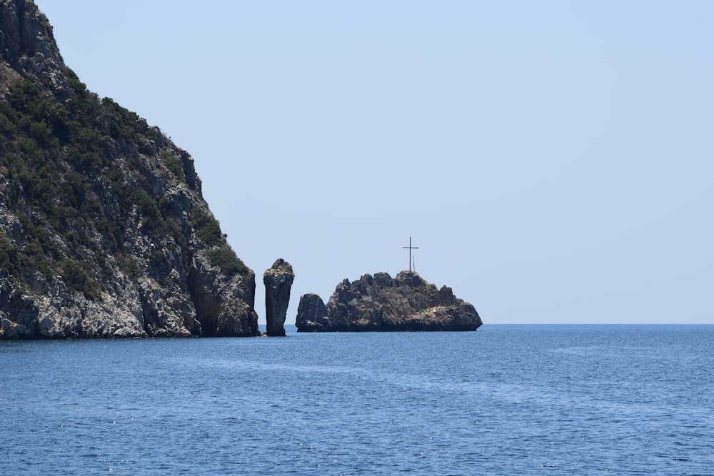 cross on top of big rock viewing blue calm sea