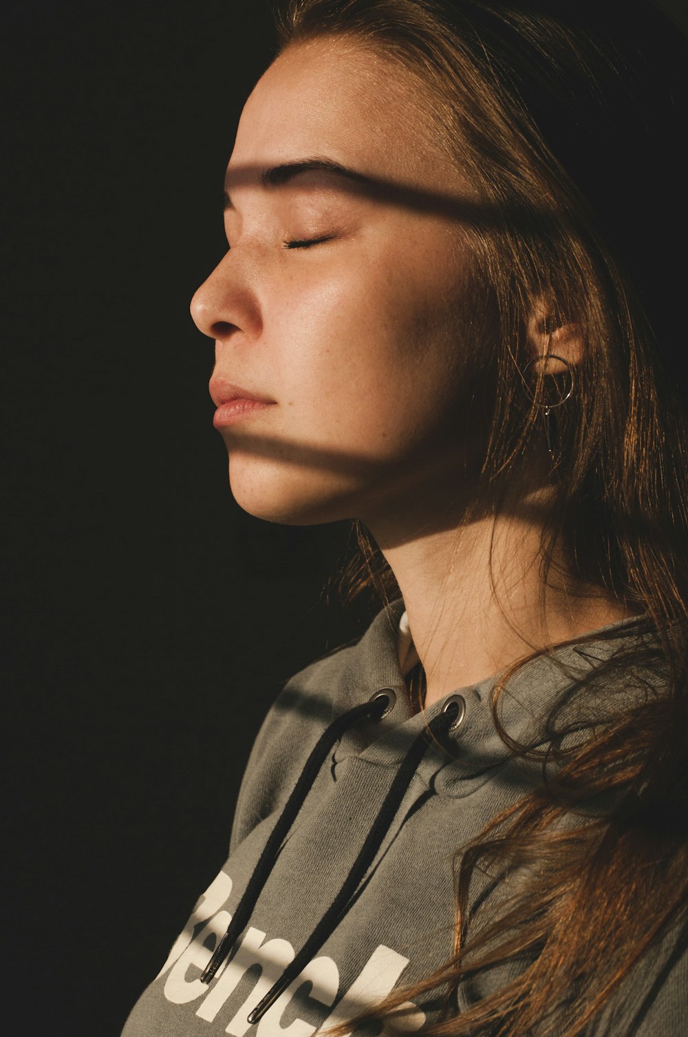 woman wearing gray top closing eyes