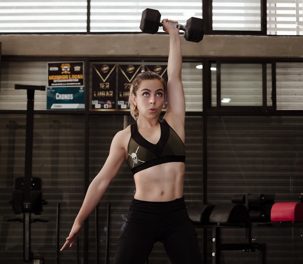 Femme faisant de l’exercice avec un haltère à l’intérieur du gymnase