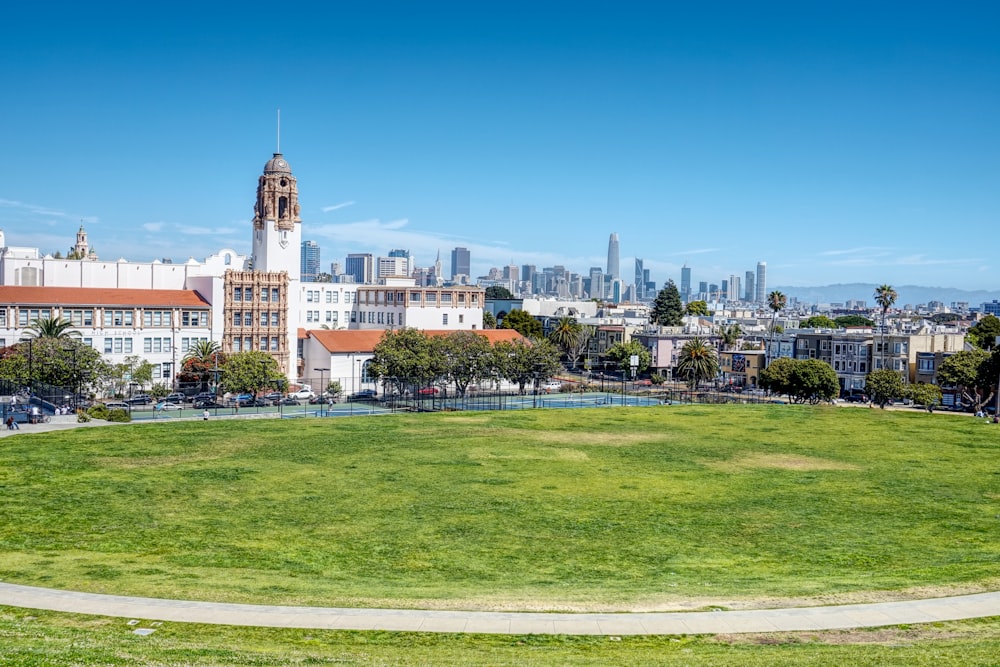 green grass field in front of white and brown building