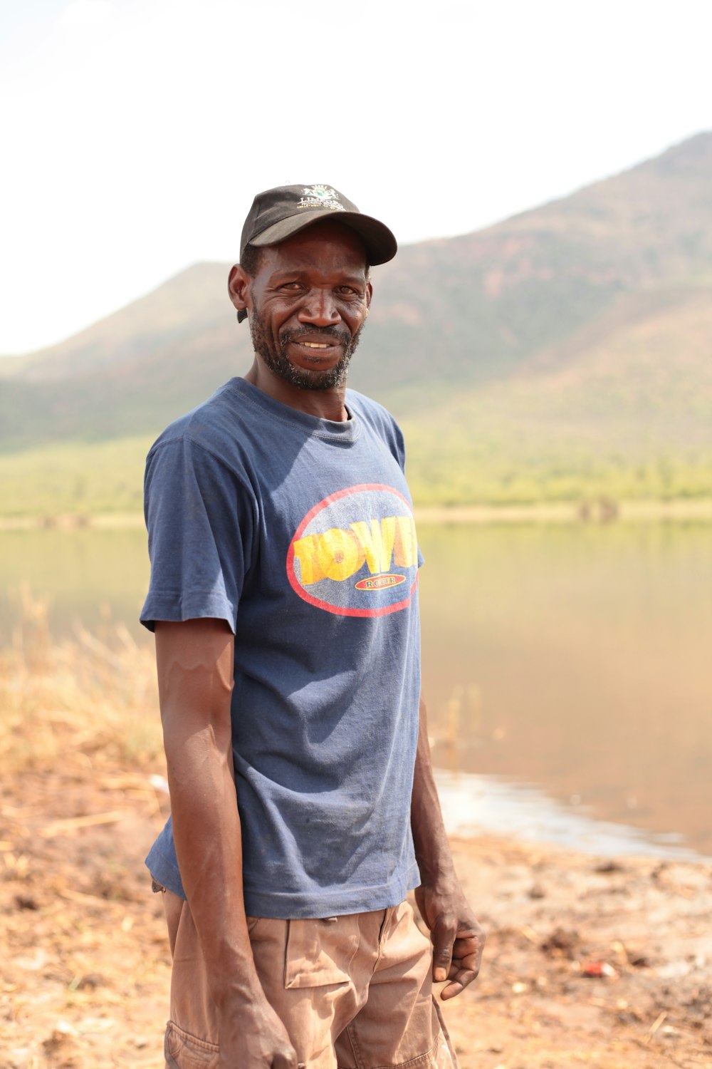 man in blue beside a lake