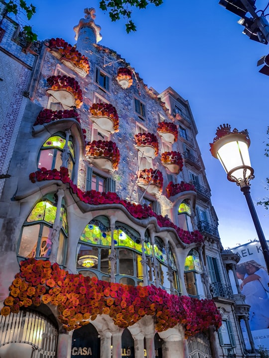 white concrete building viewing lighted lamp post at night in Casa Batlló Spain