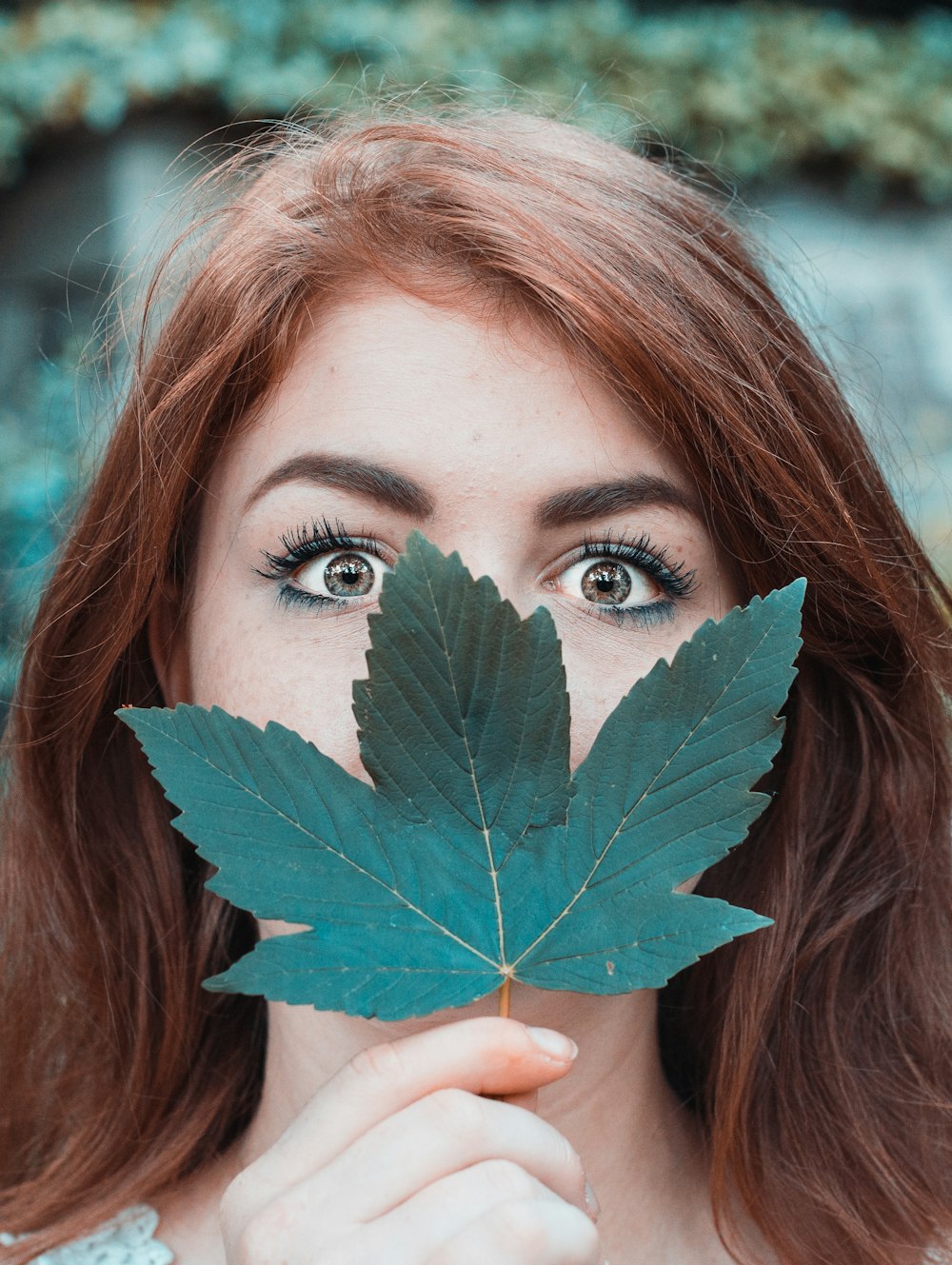 woman covering face with maple leaf