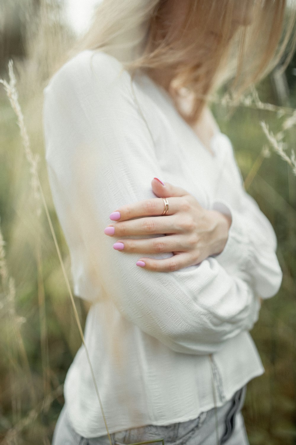 woman in white long sleeved shirt and blue denim jeans in middle of grass field