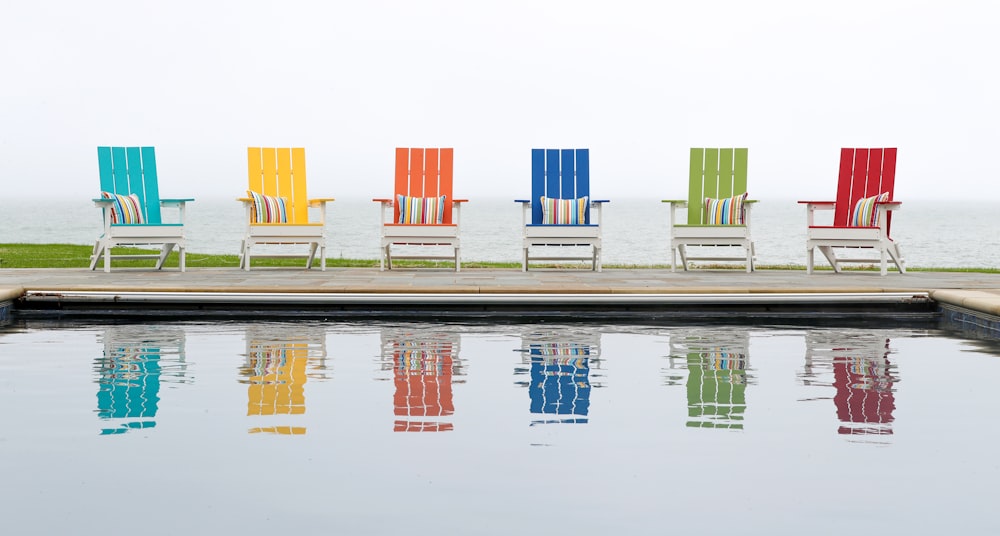 six assorted-color outdoor chairs in front of swimming pool