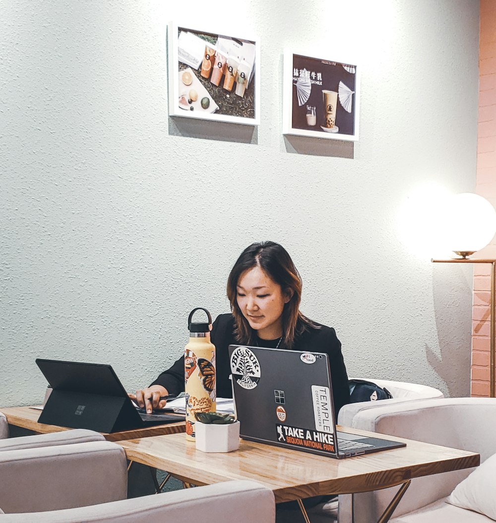 woman sitting behind table with black laptop computer