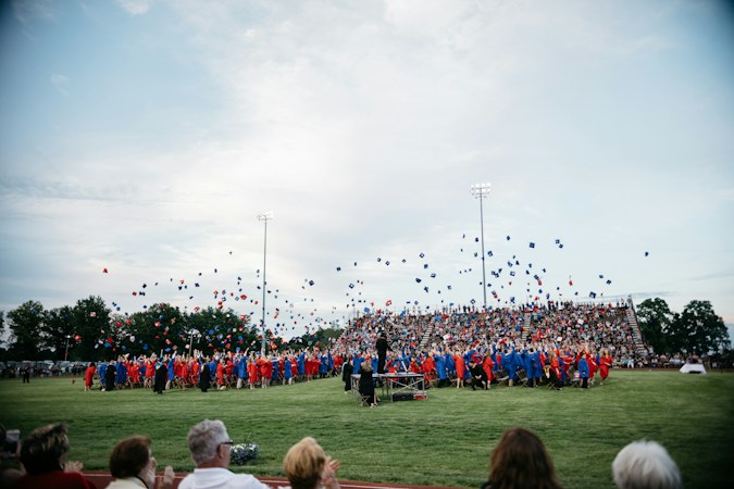 A group of graduating students tossing mortarboards at a high school ceremony