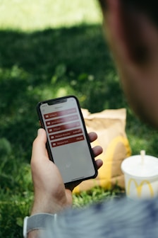 persona viendo iphone con un mcmenu de mcdonalds