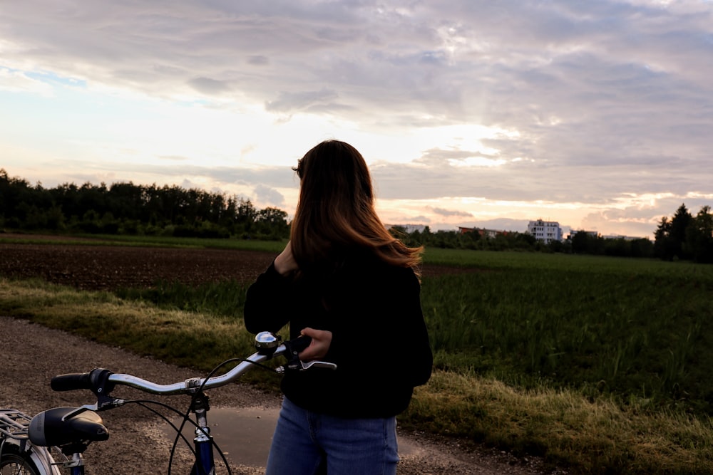 Mujer de pie en el camino de tierra sosteniendo la bicicleta