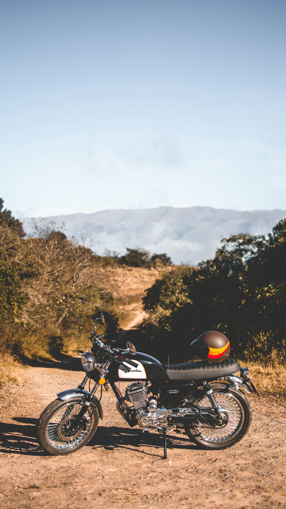 黒と白の標準的なオートバイに黒とオレンジのヘルメット