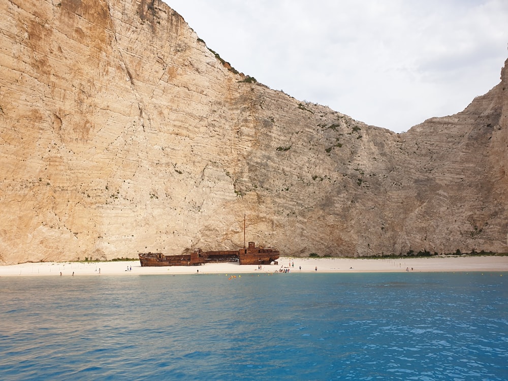 brown ship on shore near brown mountain