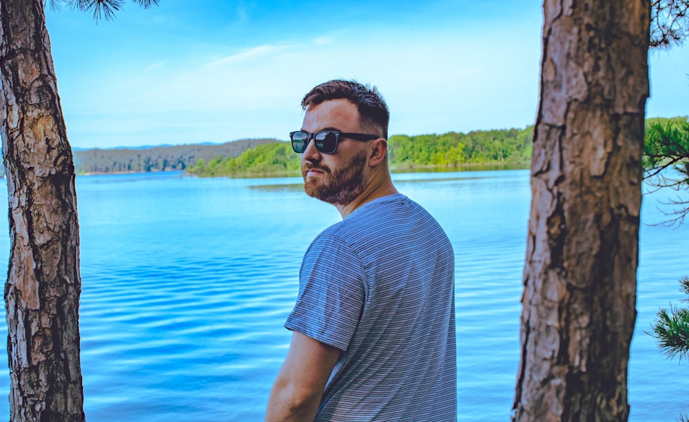 man standing and glancing his left side beside trees