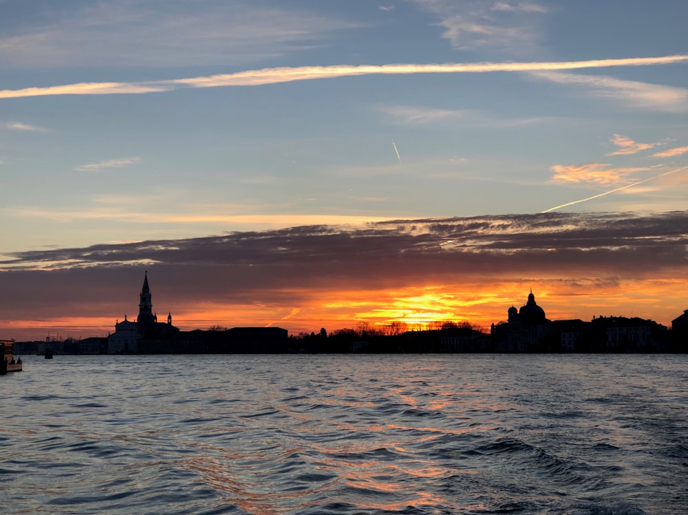 Fotografia di silhouette di case accanto allo specchio d'acqua