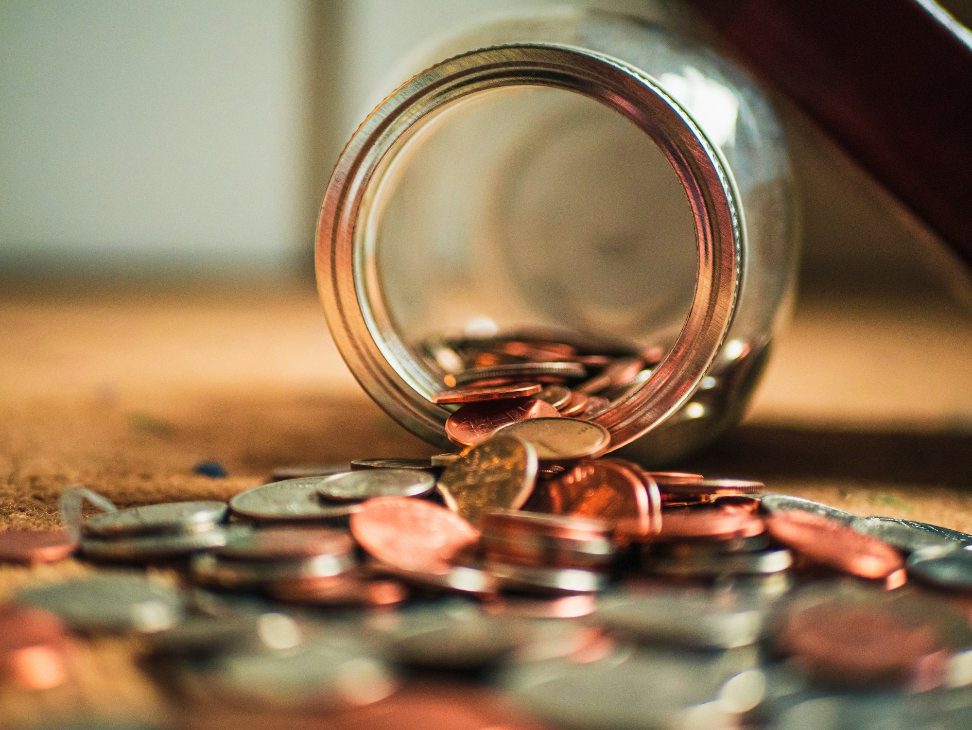 Bronze and silver coins spilling out of a glass jar.