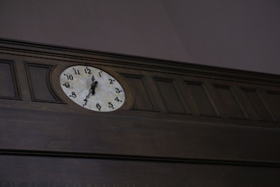 A wall clock with a classic design displayed in a cozy office setting.