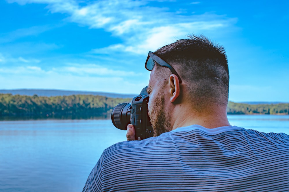 Mann fotografiert ruhiges Meer unter blauem und weißem Himmel