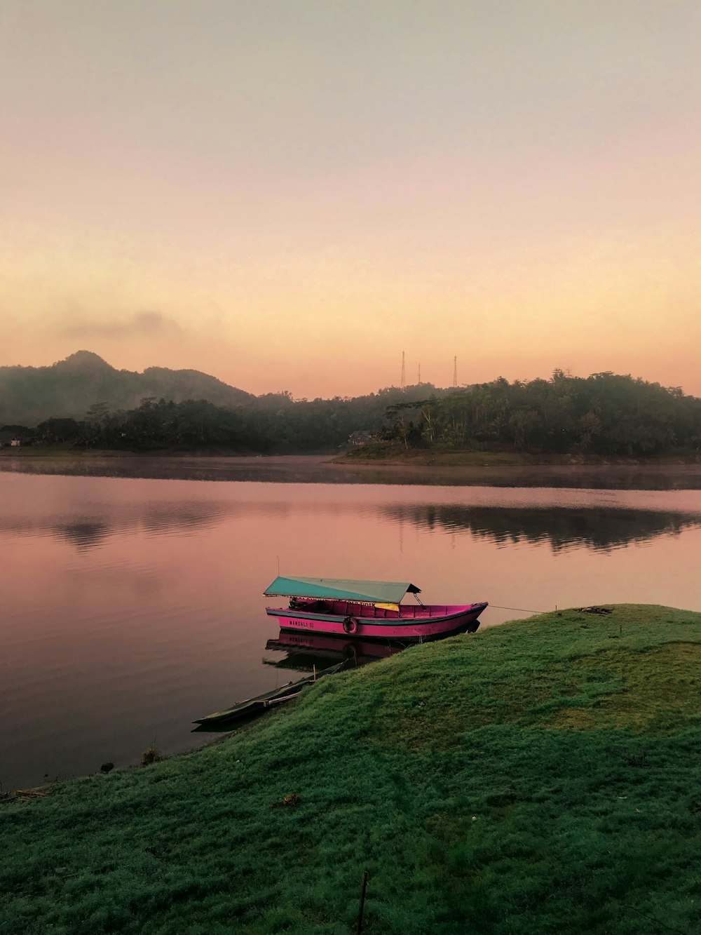 pink boat on body of water beside island