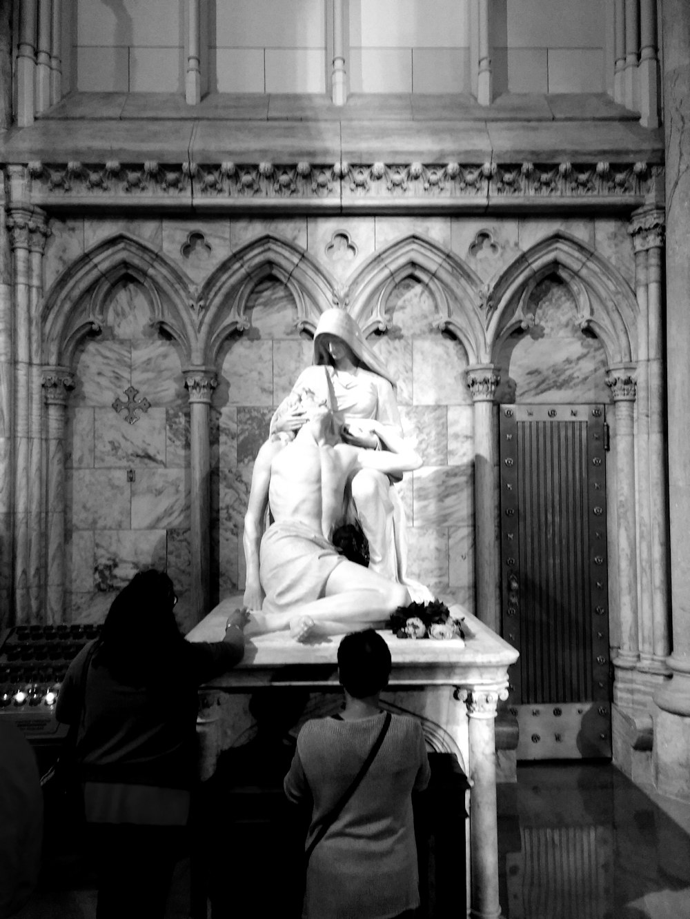 grayscale photography of two person standing near statue