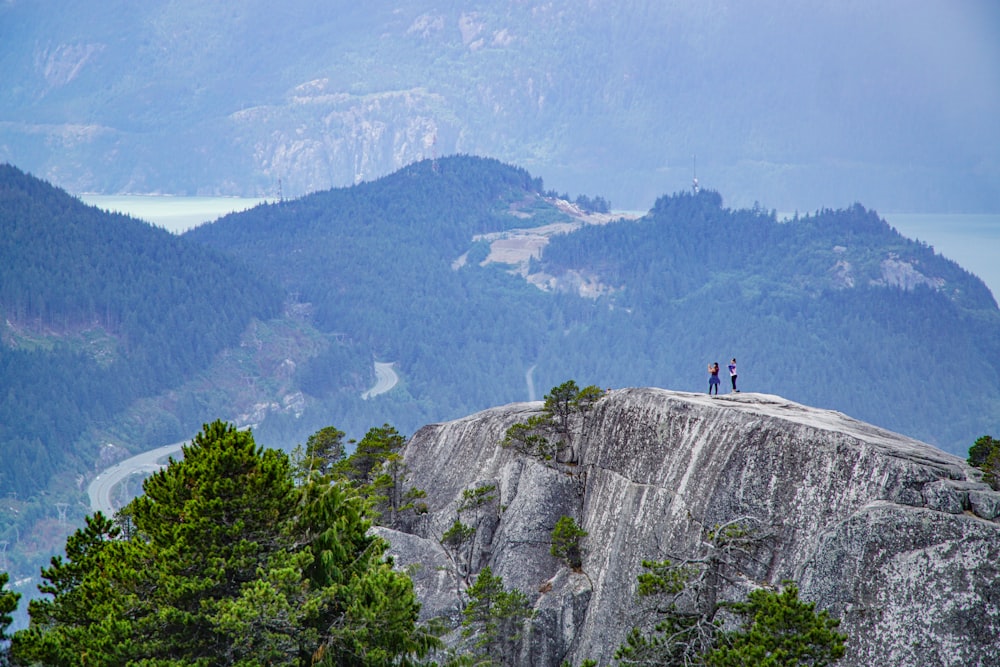 Due persone in piedi sulla cima della montagna rocciosa durante il giorno