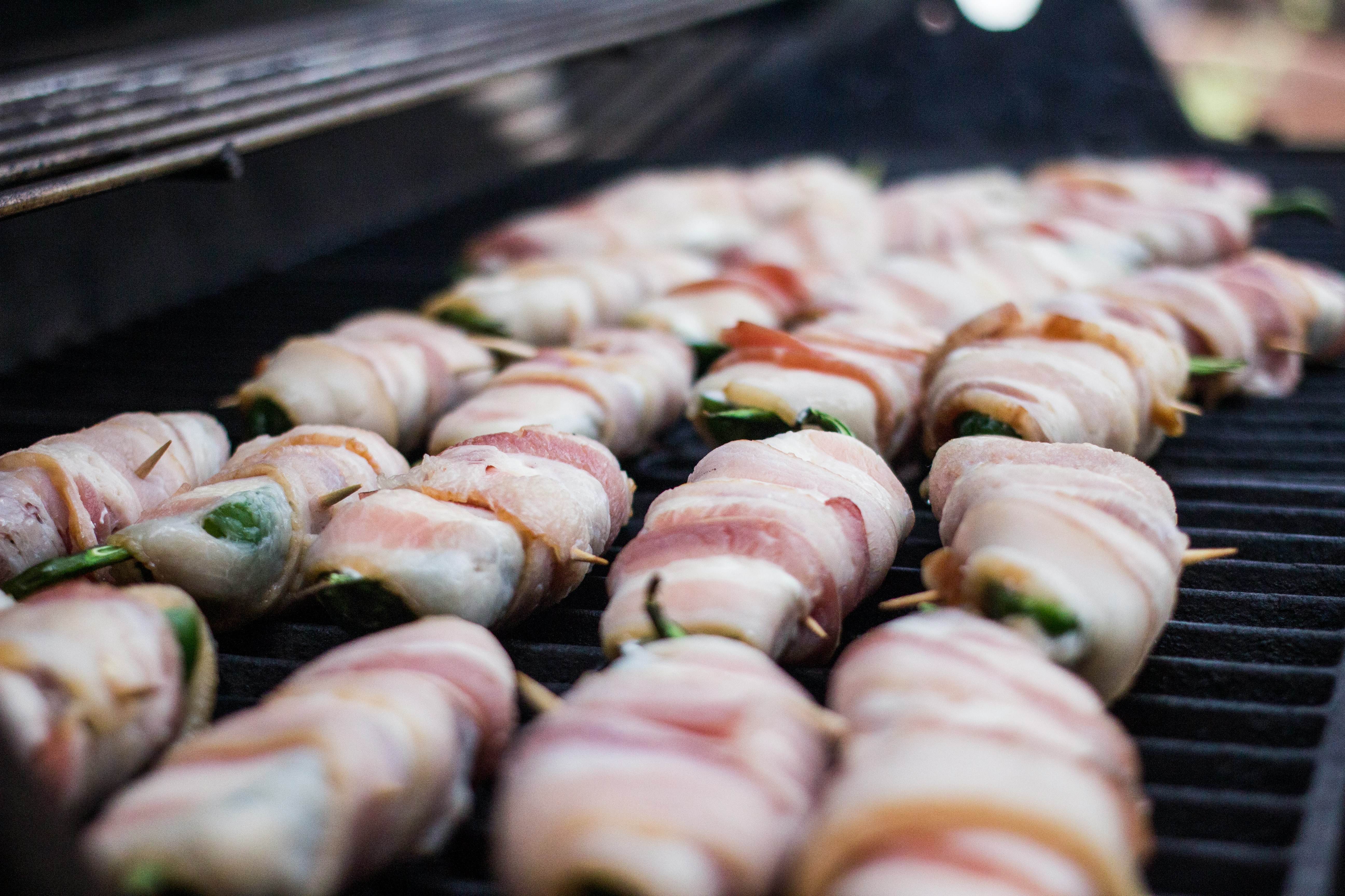 Jalapeno Poppers cooking on a propane grill. 

Bacon wrapped, cream cheese stuffed jalapenos are a must-have food for any cookout, BBQ or party.