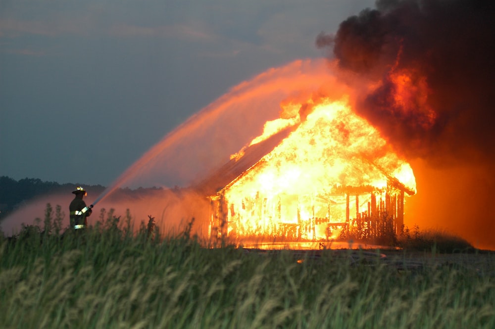 Feuerwehrmann spritzt Wasser auf brennendes Haus
