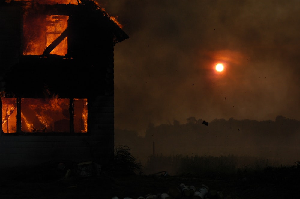 Una casa en llamas con el sol de fondo