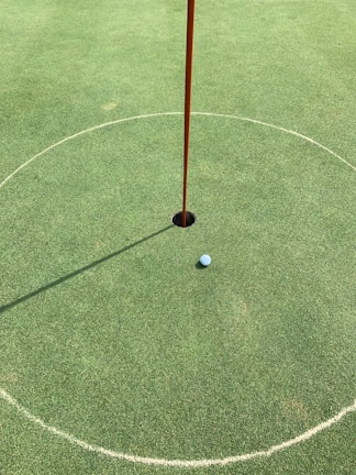 Close-up of a golf ball rolling towards the hole on a pristine putting green.