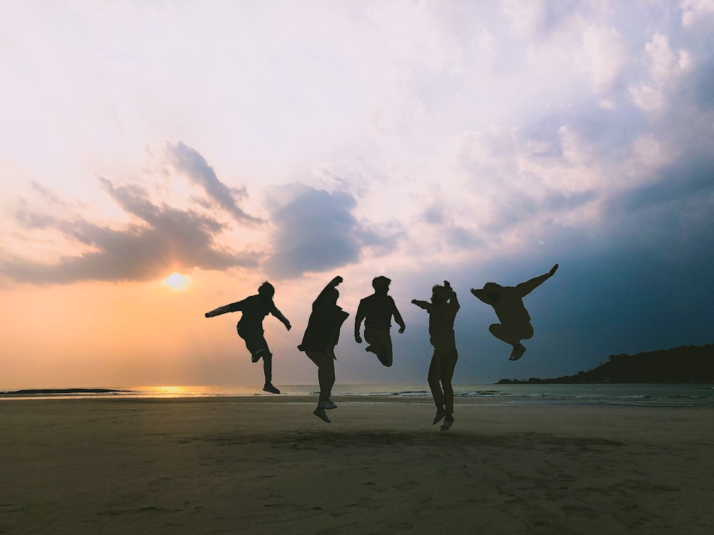group of people standing on seashore during golden hour